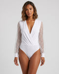 White polka dot mesh plunge wrap bodysuit by ROMAR, featuring a fitted design with long sleeves and a deep V neckline.