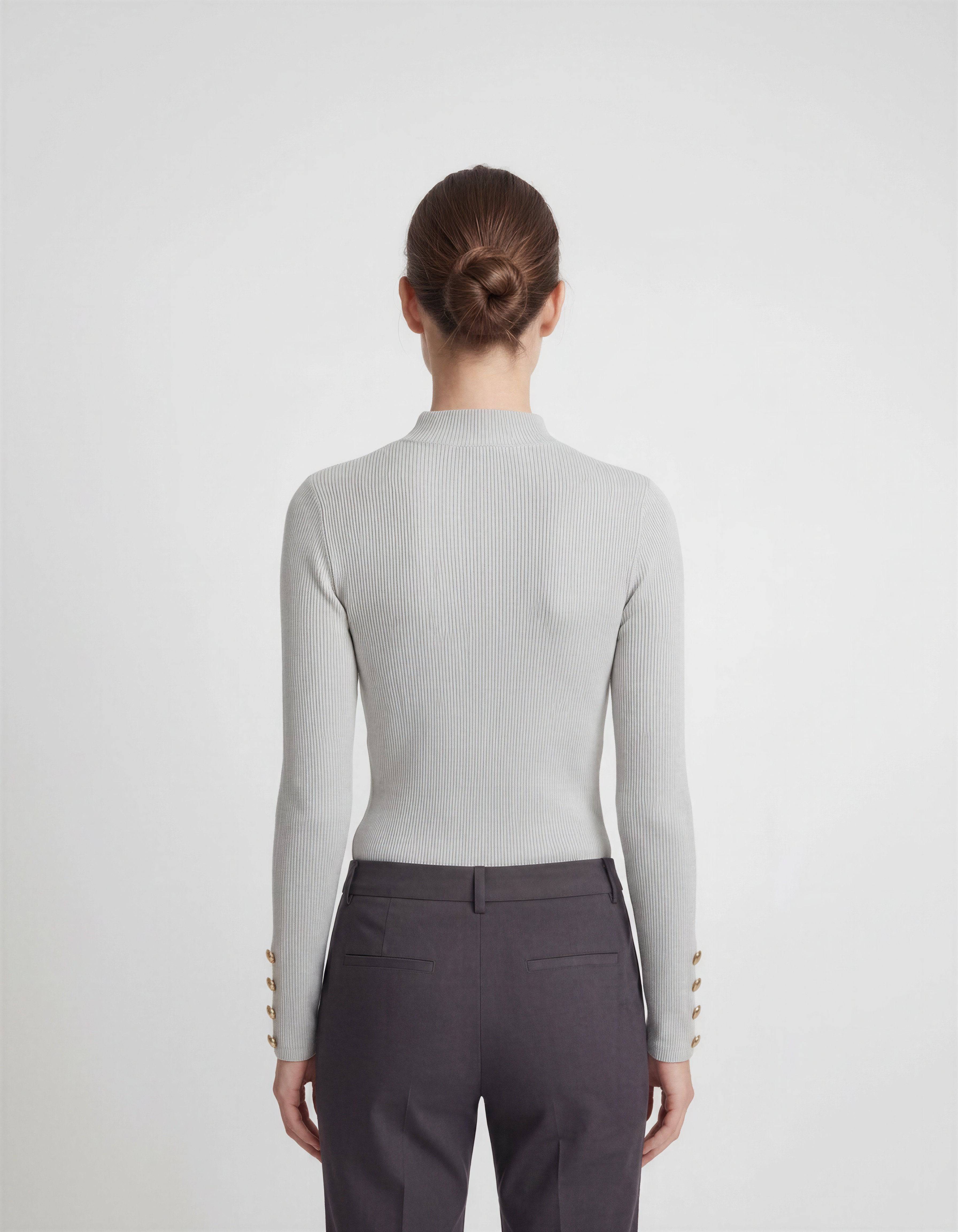 ROMAR ribbed mock neck top with gold button cuffs, showcasing a fitted knit design and stylish button details.