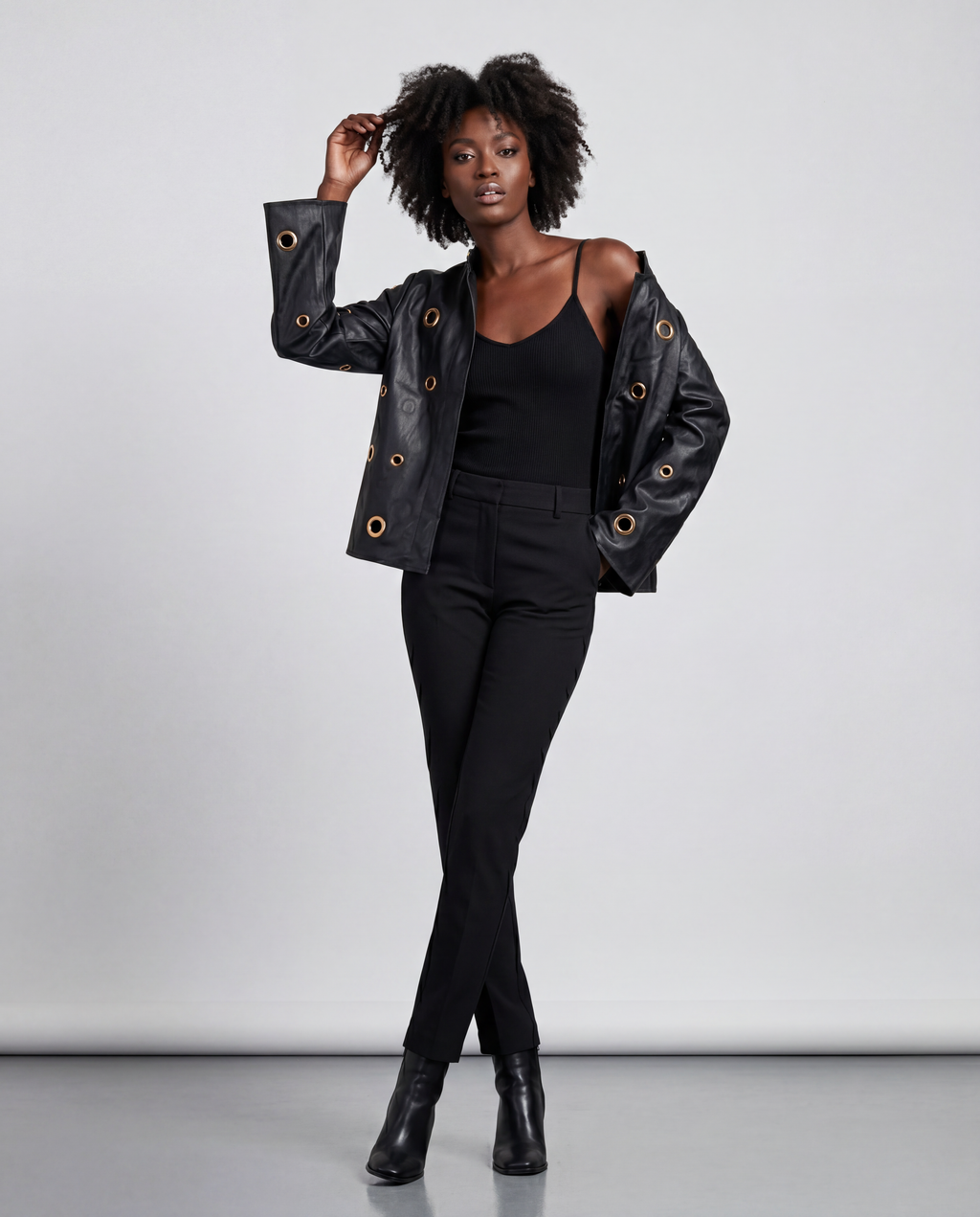 Gold eyelet embellished faux leather jacket by ROMAR, featuring stylish design and metal eyelet details on the jacket front.