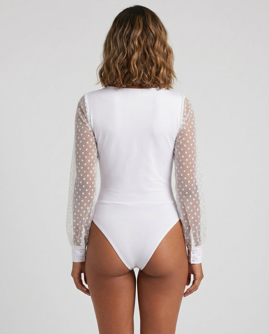 White polka dot mesh plunge wrap bodysuit by ROMAR, featuring a fitted design and deep V neckline, displayed on a mannequin.